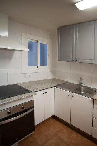 a kitchen with white cabinets and a sink at Ático del Holandés in Balaguer