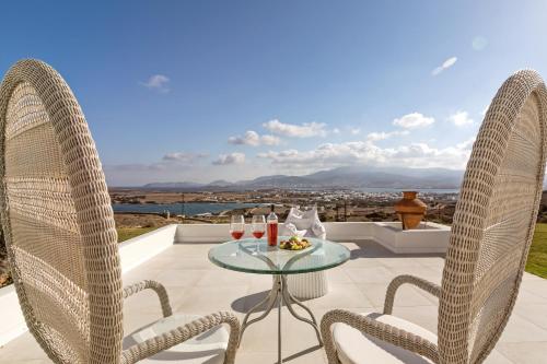 a patio with two chairs and a table with glasses of wine at On The Rocks Antiparos in Antiparos Town