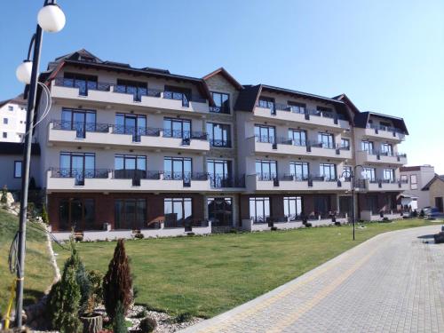 a large building with a lawn in front of it at Apartman Sladjana Premier 12 Milmari in Kopaonik