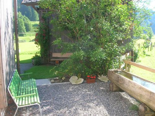 a green bench sitting next to a tree at Ferienwohnung Vogt in Mellau