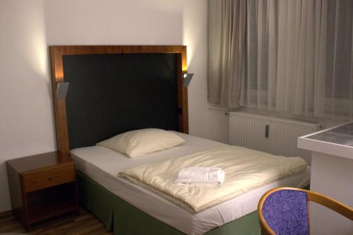 ヴォルフスブルクにあるPorschepensionの小さなベッドルーム(黒いヘッドボード付きのベッド1台付)