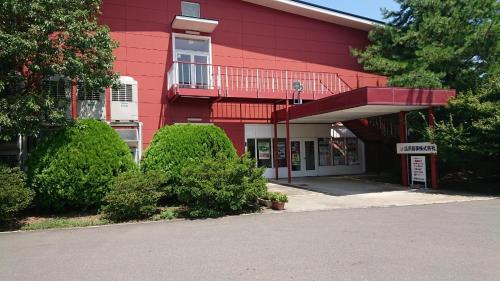 a red building with a balcony on the side of it at The Hirosawa City Dome House West Building / Vacation STAY 6890 in Chikusei