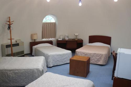 a room with three beds and a cross on the wall at The Hirosawa City Dome House West Building / Vacation STAY 7781 in Chikusei