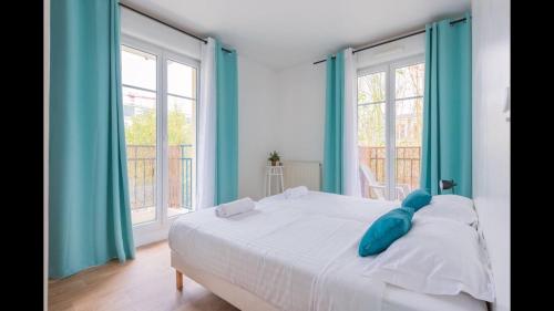 - un lit blanc avec des oreillers bleus dans une chambre dotée de fenêtres dans l'établissement Disney, very spacious comfortable 3 bedrooms family apartment, 8 pers, wifi, NETFLIX, à Chessy