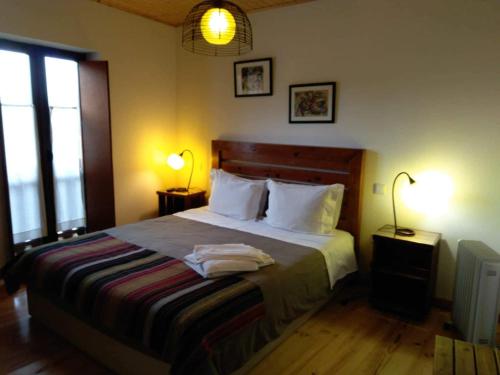 a bedroom with a large bed with two lamps on it at Pátio do Xisto in Gondramaz