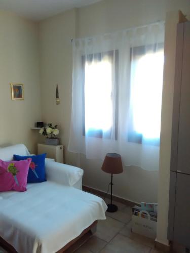 ein Schlafzimmer mit einem weißen Bett und zwei Fenstern in der Unterkunft Sole Mio in Milína