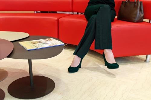 a woman is sitting on a red couch at Ibis Barcelona Santa Coloma in Santa Coloma