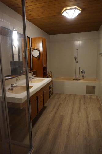 a bathroom with two sinks and a tub and a mirror at Hotel Untermetzger in Zell am Ziller