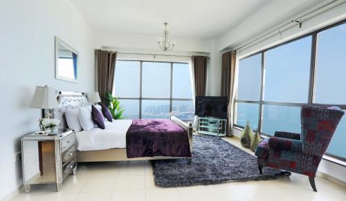 a bedroom with a bed and a chair and large windows at Luxury Casa - Marvel Sea View Apartment JBR Beach 2BR in Dubai