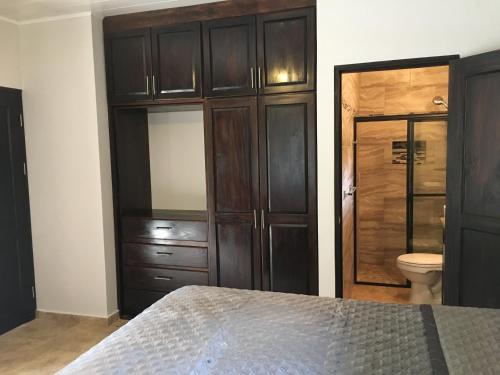 a bedroom with a bed and a toilet and cabinets at Finca Caramelo in Boquete