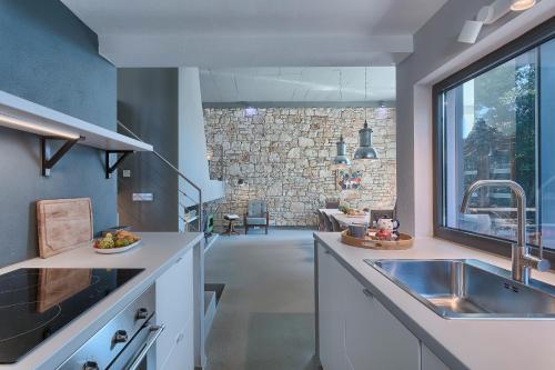 a kitchen with a sink and a stone wall at Casa Mia Apartments in Premantura