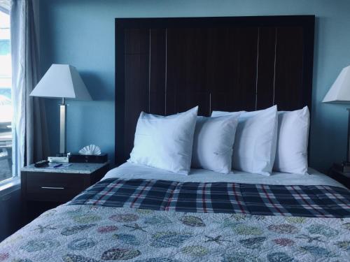a bedroom with a bed with a black headboard and white pillows at Dolphin Cove Motel in Pismo Beach