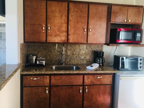 a kitchen with wooden cabinets and a sink and a microwave at Dolphin Cove Motel in Pismo Beach