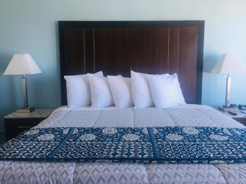 a bedroom with a large bed with white pillows at Dolphin Cove Motel in Pismo Beach