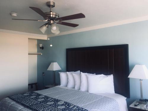 a bedroom with a bed with a ceiling fan at Dolphin Cove Motel in Pismo Beach
