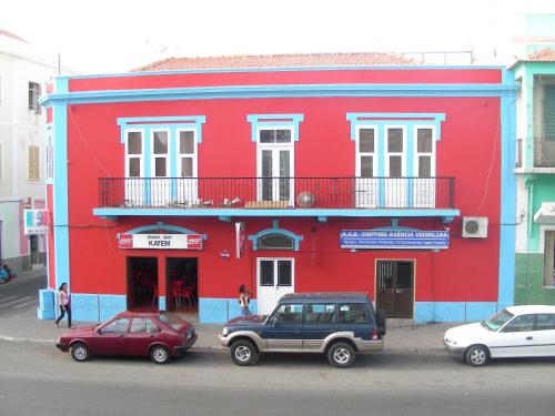 a red building with cars parked in front of it at La Residencia in Mindelo