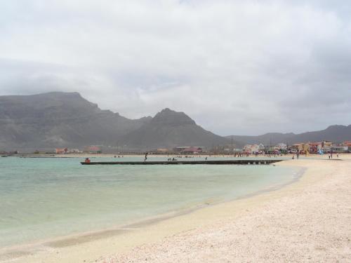 a beach with a pier and mountains in the background at La Residencia in Mindelo