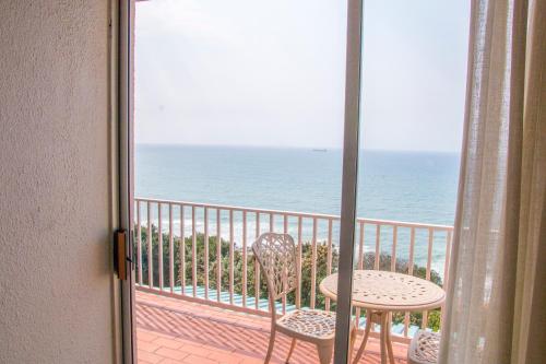 a view of the ocean from a balcony with a table and chairs at Sands Beach Breaks Umdloti Beach View in Umdloti