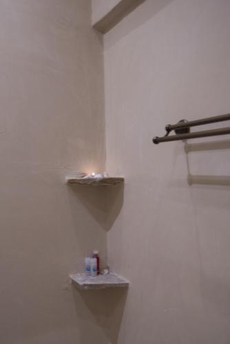 a bathroom with a white wall with two shelves at Kathara Bay Apartments in Faliraki