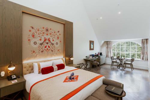 a hotel room with a large bed with a flower on it at The LaLit London in London