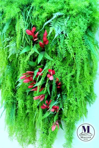 a green wreath with red flowers and green plants at Montana Hotel Songkhla in Songkhla