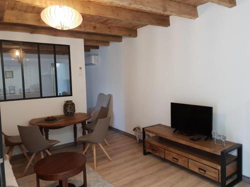 - un salon avec une télévision, une table et des chaises dans l'établissement Studio Fontaine d’amour, à Sarlat-la-Canéda