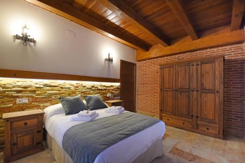 a bedroom with a large bed and a brick wall at Señorío de los Fonseca in Coca