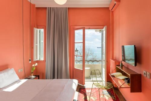 a bedroom with orange walls and a bed and a television at AiR Waterfront Nikis Apartment in Thessaloniki