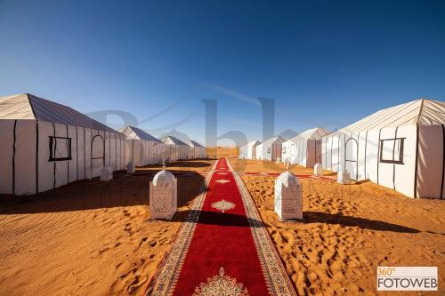 a row of houses in the desert with a red carpet at Sahara Happy Camp in Merzouga