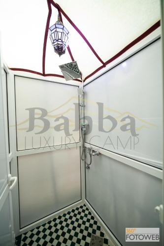 a bathroom with a glass door and a checkered floor at Sahara Happy Camp in Merzouga