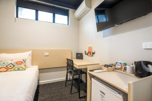 a dorm room with a bed and a desk at Nightcap at Chester Hill Hotel in Bankstown