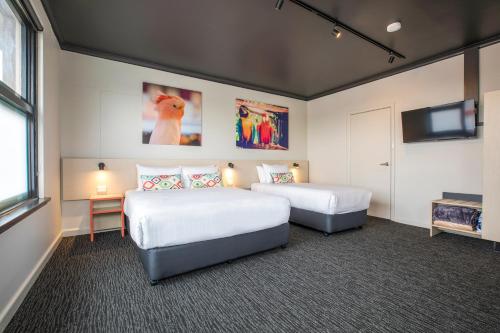 a hotel room with two beds and a flat screen tv at Nightcap at Chester Hill Hotel in Bankstown
