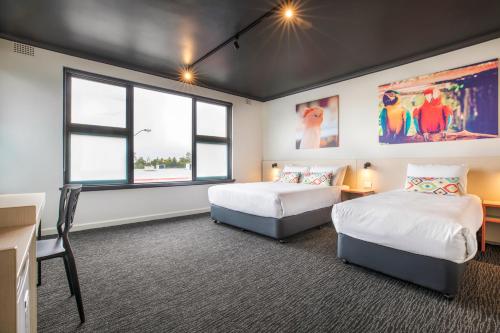 two beds in a room with two windows at Nightcap at Chester Hill Hotel in Bankstown