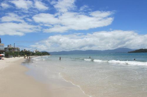 una playa con gente caminando en el agua y olas en Sobrado Vila Branca, en Florianópolis