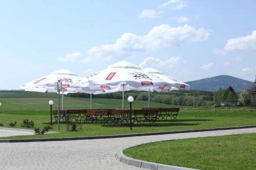 three picnic tables with umbrellas in a park at Biała Akacja Resort & Business in Prudnik
