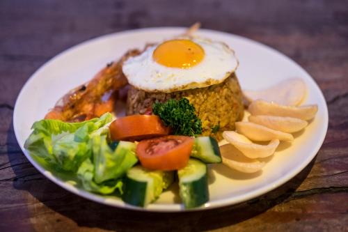 een bord voedsel met een ei en groenten bij Nick's Hidden Cottages by Mahaputra in Ubud