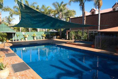 a swimming pool with a blue umbrella on top of it at Batemans Bay Marina Resort in Batemans Bay