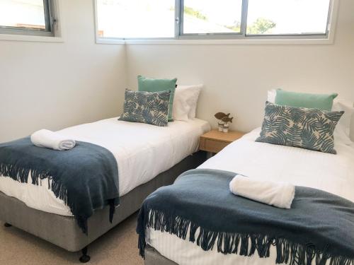 two beds in a room with two windows at Fat Frog Beach Houses in Byron Bay