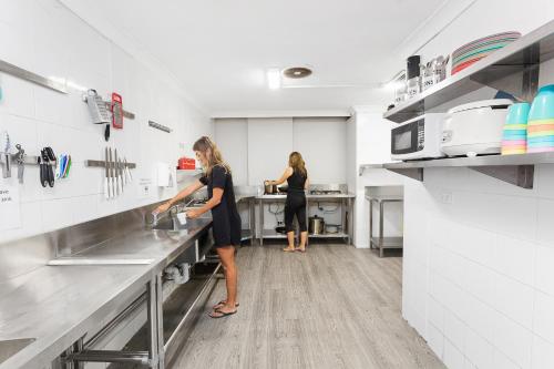 a woman and a man in a kitchen at Sydney Backpackers in Sydney