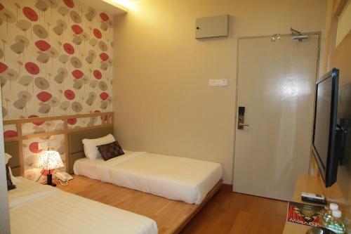 a small room with two beds and a television at De Residence Hotel in Ipoh