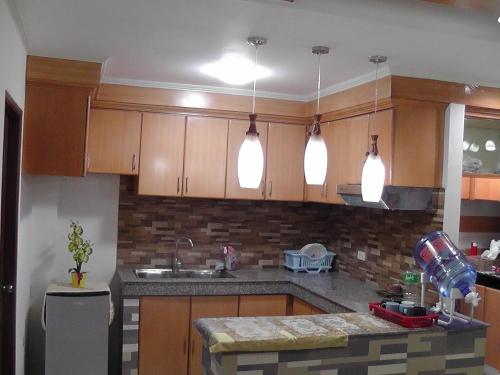 a kitchen with wooden cabinets and a counter top at Mary Chiang Baguio Transient House in Baguio