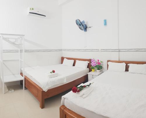 Dos camas en una habitación blanca con flores. en Hai Phuong Tuyen Guesthouse, en Phu Quoc