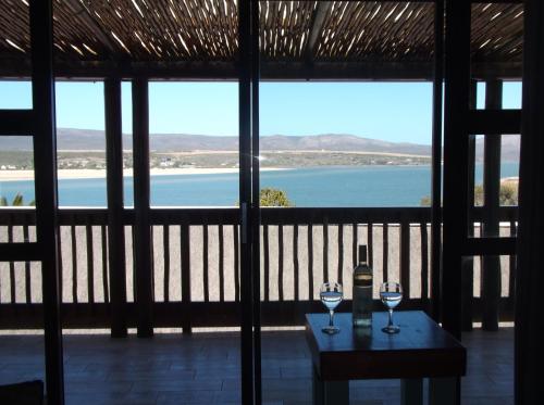 two glasses of wine on a table in front of a window at Luxury Breede River View at Witsand- 300B Self-Catering Apartment in Witsand