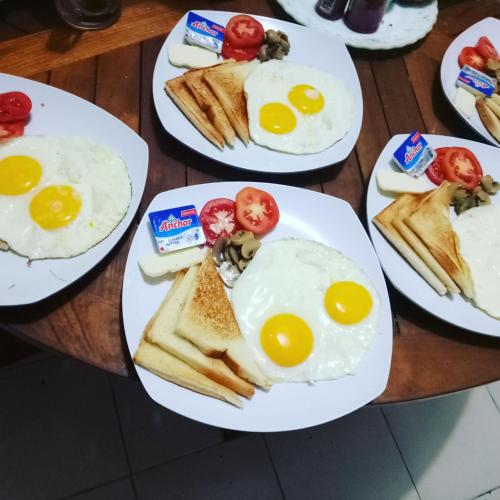 a table topped with plates of eggs and toast at Pujihouse One in Legian