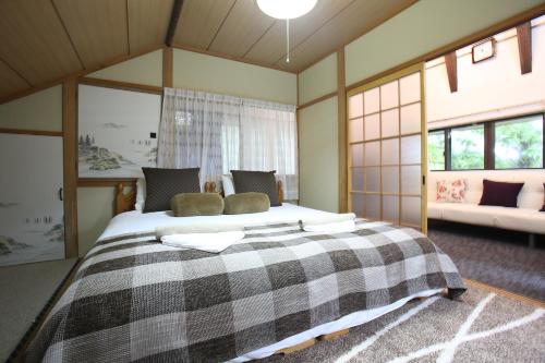 1 dormitorio con 1 cama grande con manta a cuadros en Powder Peak Misorano Free courtesy car en Hakuba