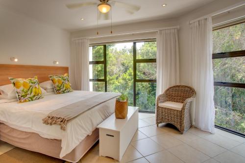 ein Schlafzimmer mit einem großen Bett und großen Fenstern in der Unterkunft Limoni Luxury Suites in Plettenberg Bay