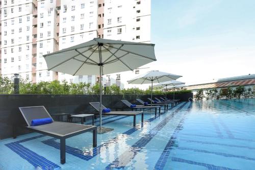 a row of chairs and umbrellas next to a swimming pool at Citadines Central Binh Duong in Thuan An