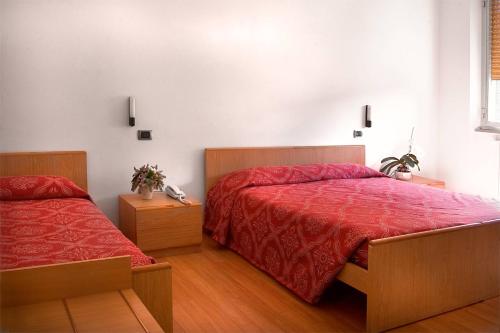 a bedroom with two beds with red comforter at Hotel Ristorante Anita in Cupra Marittima