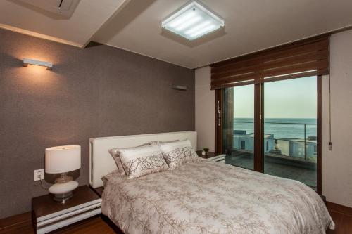 a bedroom with a bed with a view of the ocean at Sun Village in Seogwipo