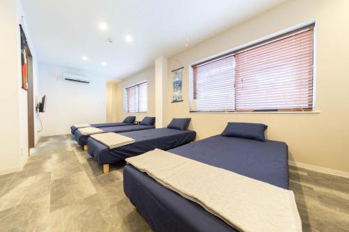 a room with three beds and a window at Guest House MEGU-chan in Osaka